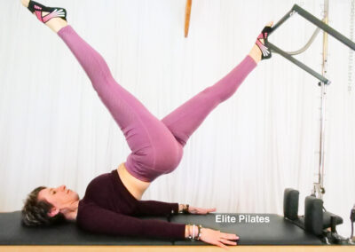 Pilates tower instructor on the Tower bed doing exercise